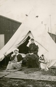 La hermana Eleanor Wibmer Jeffries y la hermana Nellie Constance Morrice (derecha) fuera de su tienda en el Hospital General Australiano No. 3 con flores recogidas de la orilla del Somme, c. junio de 1917 (foto en blanco y negro) de Australian Photographer