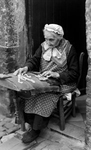 Encajera, una mujer mayor, en Brujas está sentada a la puerta de su casa mientras hace encaje... de B. Anthony Stewart
