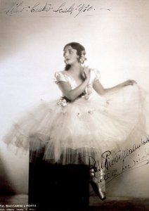 Retrato de la bailarina clásica Rosa Piovella Ansaldo, en tutú y zapatillas de ballet. Está sentada, de frente, con la cara vuelta hacia un lado. Rosas de tela decoran su vestimenta y su cabello cuidadosamente arreglado (Milán, Teatro alla Scala) de Baccarini and Porta