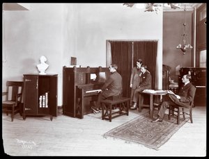 Cuatro hombres, uno tocando un piano de la compañía H. Bruman Co., 1907 de Byron Company
