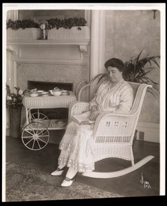 La Sra. Howard sentada con un libro en una mecedora en su casa en 200, 5th Avenue, Nueva York, 1915-6