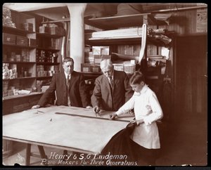 Retrato de Henry y S.G. Lindeman con su hijo o nieto sobre planos de una tienda para un piano