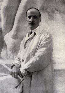 Retrato de tres cuartos del escultor Edoardo Rubino con martillo en mano. En el fondo se puede distinguir una escultura de Carlo Gherlone