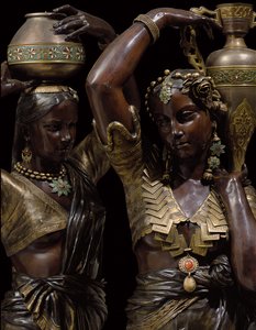 Detalle de dos antorchas de bronce en forma de mujeres indias llevando jarrones