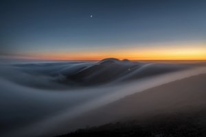 Las montañas al atardecer sobre las nubes