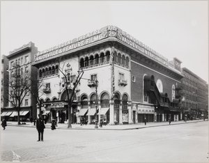 Un gran teatro con una fachada elaborada, completa con arcos moriscos y balcones. Un gran cartel en la parte superior del edificio dice 