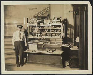 Vendedor de periódicos ciego, John Martie, en su puesto en el extremo sur del Edificio Municipal, Nueva York de Company Byron