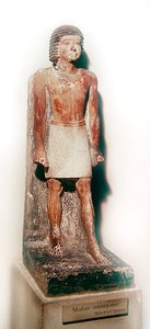 Estatua de un hombre de pie con un shenti blanco