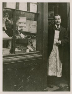 Un tendero de pie en la puerta de su tienda de English Photographer