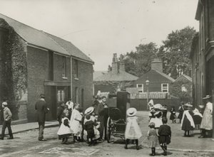 Multitud de niños se reúne alrededor de un órgano de calle de English Photographer