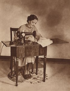 Ama de casa trabajando con la máquina de coser, mediados de la década de 1930 (fotografía en blanco y negro). de English Photographer