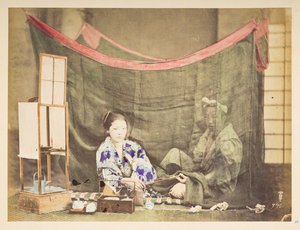 pareja japonesa en su tiempo libre, Cuadro de estudio de una joven japonesa, sentada con un impedimento para preparar té a su alrededor, entregando una pipa a una figura masculina que se sienta detrás de ella, protegida por un mosquitero de lino,   Fotógra de English Photographer
