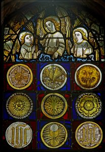 Un panel en la ventana este que representa ángeles sobre 9 medallones con resplandores solares, rosas, una cabeza de leopardo, un cáliz y monogramas