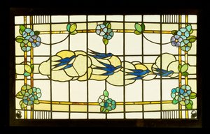 Panel de Artes y Oficios de un grupo de golondrinas ante nubes en un borde de cabezas de flores estilizadas