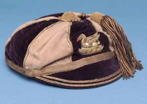 Gorra de fútbol segmentada azul y blanca con insignia de dragón de metal y borla dorada