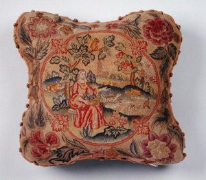 Cojín, bordado en petit point, que representa a una mujer en un paisaje de English School