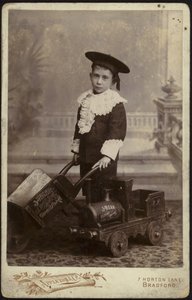 Retrato de un niño pequeño posando con un carrito de mano de English School