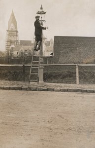 Hombre en una escalera arreglando una lámpara de calle de European Photographer