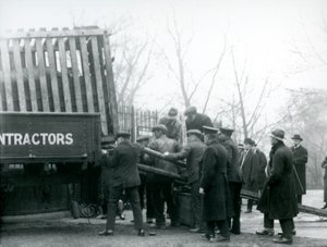 Una multitud de espectadores observa mientras un rinoceronte es descargado de un camión por los cuidadores en el Zoológico de Londres en 1924 de Frederick William Bond