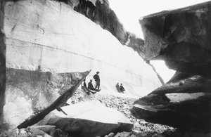 Algunos hombres sentados a lo largo de las paredes de una cantera de mármol, en los Alpes Apuanos (foto en b/n) de G. Armani