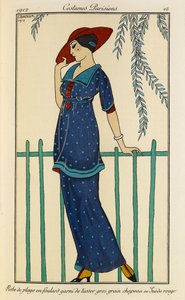 Bata de playa en foulard garni de tussor gros grain chapeau en Suède rouge. Costumes Parisiens nº 15. Mujer con vestido de playa y pañuelo de seda cruda ribeteado de grosgrain en azul moteado y sombrero rojo. de Georges Barbier