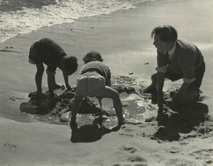 Tres niños jugando con arena en la playa.