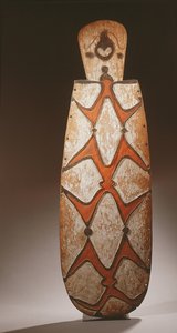 Escudo ovalado Asmat, tallado en relieve con figuras estilizadas, una máscara en la parte superior de Guinean New