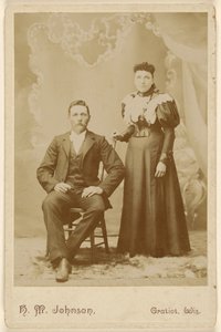 [Pareja no identificada: hombre con bigote sentado, mujer de pie] de H. M. Johnson