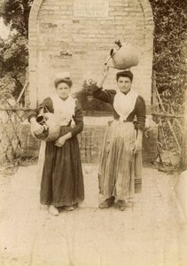 Dos mujeres jóvenes con trajes tradicionales y jarras de terracota cerca de un pozo, Las Marcas, Italia, hacia 1910. de Italian Photographer