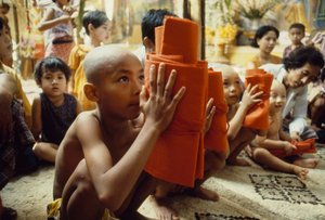 Un joven con la cabeza rapada recibe su vestimenta de monje. Mandalay, Birmania. de James L Stanfield