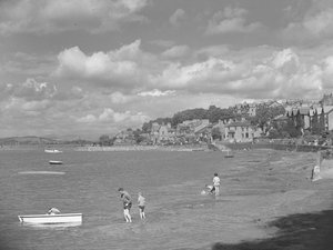 Gente jugando en barcas con el agua alta en Arnside con el Hotel Albion al fondo.