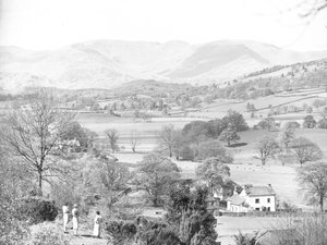 Tres mujeres de pie mirando a través de un lago en Esthwaite, fells en el fondo