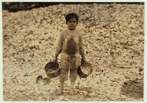 Manuel, recolector de camarones migrante de 5 años, frente a un montón de conchas de ostras, trabajando por segundo año en Dunbar, Lopez, Dukate Company, Biloxi, Mississippi, 1911