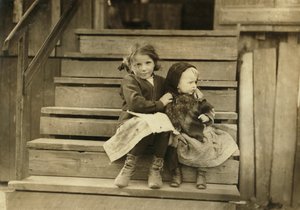 Retrato de una niña cuidando a su hermana bebé mientras el resto de la familia trabaja en la conservera local, Bayou La Batre, Alabama, EE.UU.