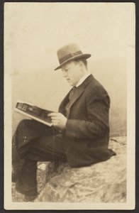 Hombre leyendo una revista sobre una roca