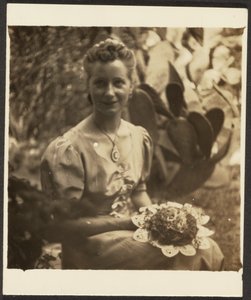 [Mujer con ramo de flores sentada ante un cactus]