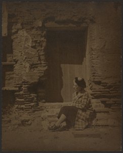 [Mujer sentada frente a un edificio en mal estado] de Louis Fleckenstein