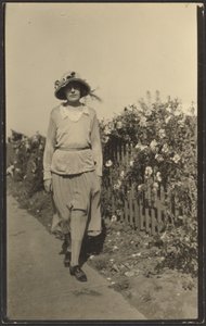 [Mujer caminando por la valla con flores]