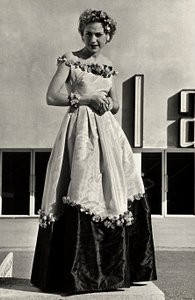 Modelo en vestido de gala creado por la casa de alta costura "Graldi". El artículo se caracteriza por un escote bajo y una falda completa decorada con apliques florales.