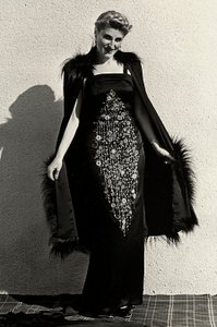 Modelo en vestido de noche creado por la casa de alta costura "Graldi". El artículo se caracteriza por un rico bordado y se completa con una capa con ribete de piel.