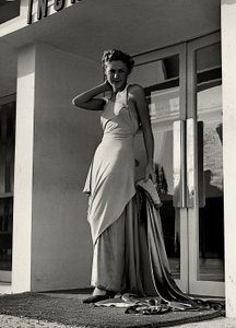 Modelo en vestido de noche creado por la casa de alta costura "Graldi". El artículo se caracteriza por un escote pronunciado adornado con tirantes de pedrería y una larga cola.