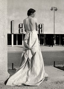 Modelo vista desde atrás lleva un vestido de noche creado por la casa de alta costura "Lamma". El artículo se caracteriza por una espalda baja y una larga cola. de Luis Bogino