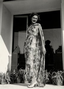 Modelo con un vestido largo con patrón floral creado por la casa de alta costura "Graldi". El artículo se complementa con un manto del mismo tejido.