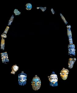 Collar de pasta de vidrio con colgantes que representan cabezas con barba, originalmente de Olbia, ahora conservado en el Museo Arqueológico Nacional de Cagliari