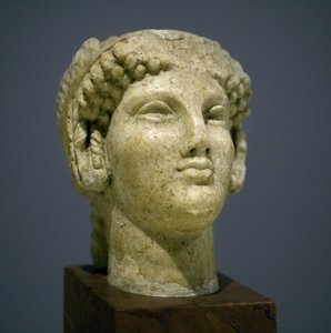 Cabeza de niña (Kore), escultura del período helenístico romano (siglo III-II después de nuestra era), rostro muy expresivo, pómulos prominentes hacia el este, sonrisa, cabello rizado, estilo arcaico de Ionia en el siglo VI antes de nuestra era que se perp de Roman