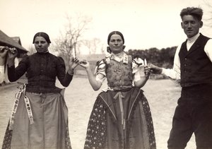 Dos damas y un hombre, vestidos con trajes tradicionales húngaros, bailan cogidos de la mano, con unas velas en las manos de Rudolf Balogh