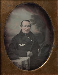 Hombre con abrigo y guantes, sosteniendo un sombrero, sentado frente a un fondo pintado al aire libre de Samuel Broadbent Jr..