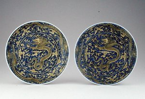 Un par de platos de dragón azul y amarillo bajo vidriado