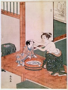 Madre desnuda lavando a su hijo en Japón cerca de una palangana llena de agua