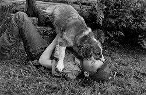 Un joven juega con su perro frente a su cabaña de madera en Palmer, Alaska